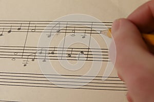 A Hand Composing Sheet Music with a Pencil