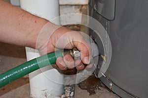 Hand Connecting Garden Hose to Drain the Water Heater