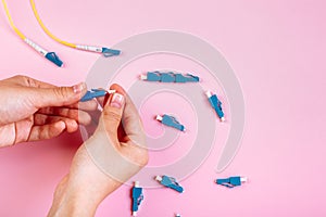 Hand connects blue LC optical attenuator on pink background