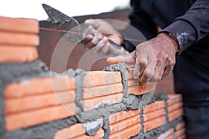 A hand of construction worker, industrial bricklayer installing bricks on construction site