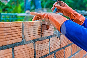 Hand of construction worker laying down brick wall one by one us