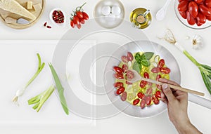 hand cooking fry and mix tomatoes sauce above saucepan with cutting board and food ingredients on kitchen white worktop, copy spa