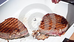 Hand covers tuna steak in soy sauce silicone brush and sprinkle spices seasoning