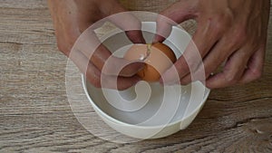 Hand cracked brown eggshell in bowl on table