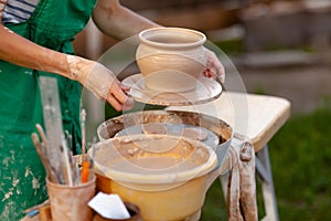 Hand craft making pottery on wheel. Female hands mold ceramic plate from clay pot