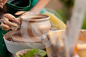 Hand craft making pottery on wheel. Female hands mold ceramic plate from clay pot