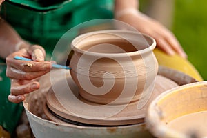 Hand craft making pottery on wheel. Female hands mold ceramic plate from clay pot