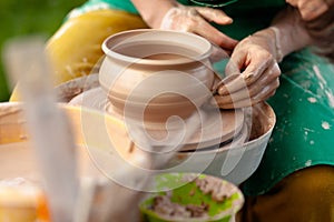 Hand craft making pottery on wheel. Female hands mold ceramic plate from clay pot