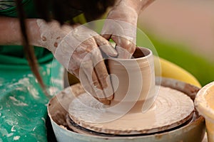 Hand craft making pottery on wheel. Female hands mold ceramic plate from clay pot