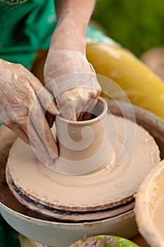 Hand craft making pottery on wheel. Female hands mold ceramic plate from clay pot