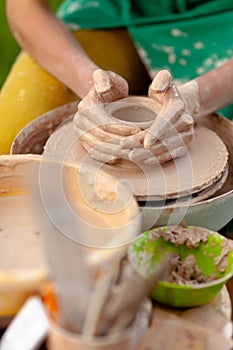 Hand craft making pottery on wheel. Female hands mold ceramic plate from clay pot