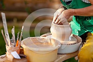 Hand craft making pottery on wheel. Female hands mold ceramic plate from clay pot