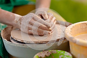 Hand craft making pottery on wheel. Female hands mold ceramic plate from clay pot