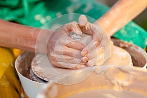 Hand craft making pottery on wheel. Female hands mold ceramic plate from clay pot