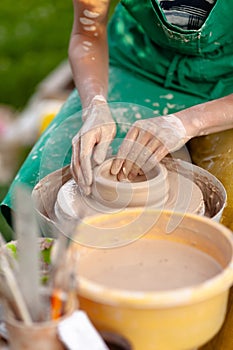 Hand craft making pottery on wheel. Female hands mold ceramic plate from clay pot