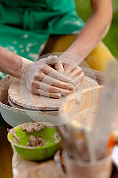 Hand craft making pottery on wheel. Female hands mold ceramic plate from clay pot