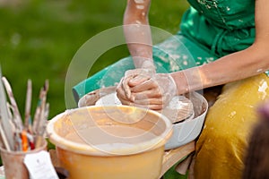 Hand craft making pottery on wheel. Female hands mold ceramic plate from clay pot