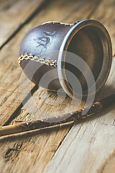 Hand Crafted Artisanal Yerba Mate Tea Leather Calabash Gourd with Straw on Weathered Plank Wood Background