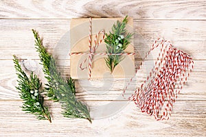 Hand crafted gift box on rustic white wooden background with Christmas decoration fir tree top view. Toned