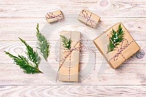 Hand crafted gift box on rustic white wooden background with Christmas decoration fir tree top view. Toned