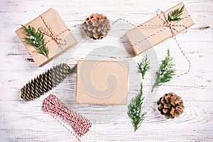 Hand crafted gift box on rustic white wooden background with Christmas decoration fir tree top view. Toned