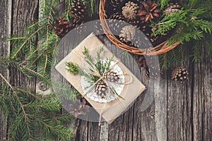 Hand crafted gift on rustic wooden background and a basket with fir branches and cones