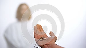 Hand with cross stretching out to Jesus, believer asking God for help, healing