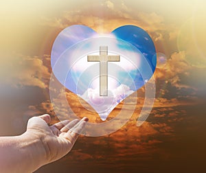 Hand with crucifix and light on heart background