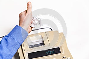Hand crumples paper check over cash register on white background