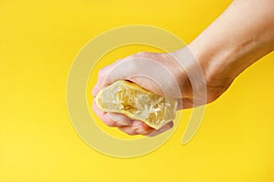 Hand crushes a piece of fresh lemon