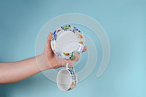 Hand and cup on blue background. Man holding White cup with pain