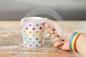 Hand with cup of cacao and gay awareness wristband