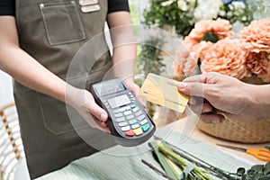 Hand of customer paying with contactless credit card in flower shop.