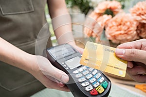 Hand of customer paying with contactless credit card in flower shop.