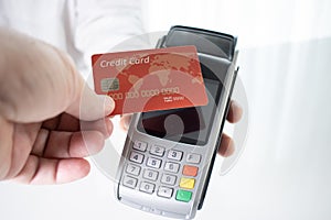 Hand of customer paying with contactless credit card with NFC technology