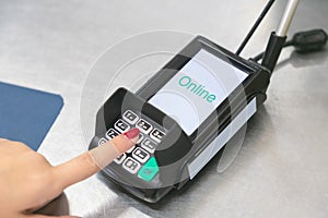 Hand of customer paying and entering security pin in credit card reader