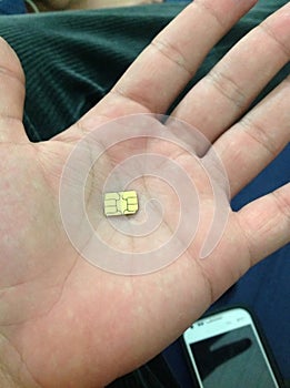 Hand-cut golden telephony chip to fit a nano chip slot, in the palm of the hand.