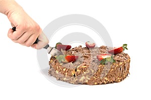 Hand cutting chocolate cake with strawberries on white