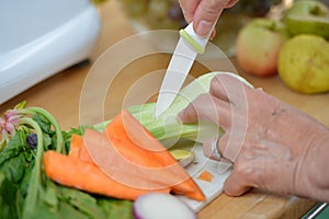 Hand cutting and putting vegetables and fruits in extractor to make delicious coloured juice