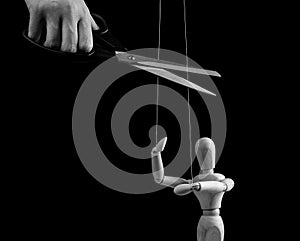 Hand cutting strings over puppet with scissors. Manipulation, negative influence, control stop concept. Overcoming