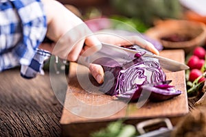 Hand cutting vegetables.Women hands is slicing cabbage on wooden board near vegetables