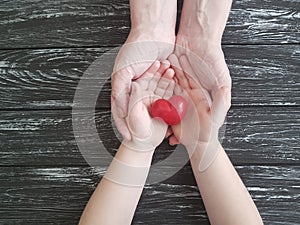 Hand dad and child heart red on black wooden photo