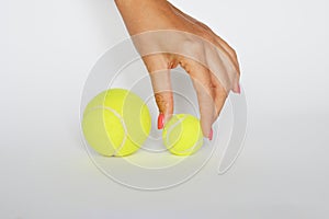 Hand of an debutant athlete choosing a small tennis ball on white background