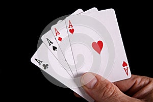 Hand with a deck of four aces card on black background