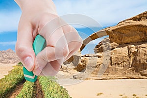 Hand deletes sand in desert by rubber eraser