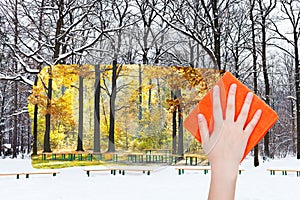 Hand deletes winter urban park by orange cloth