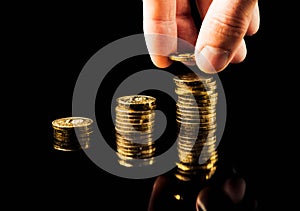 Hand deliver a stack of coins graph profit growth on black background