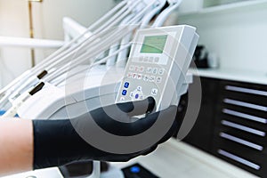 Hand of dentist in the black gloves presses the control buttons of dental chair. Medicine, stomatology concept.