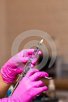 Hand of dentist in glove holding dental syringe