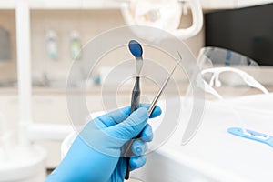 The hand of the dentist in the glove holds tool probe and mirror. . Stomatological instrument in the dentist clinic